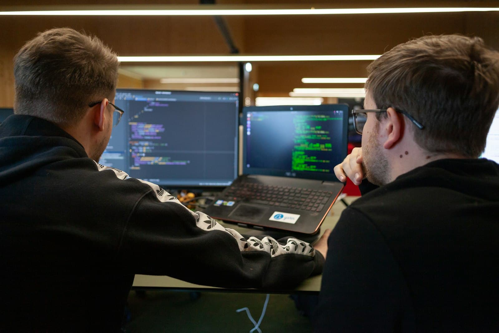 Two people reviewing software work on a laptop